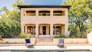 Une maison à deux étages avec une piscine, un espace salon extérieur et un barbecue.