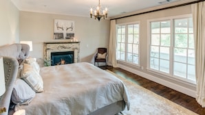 Une chambre spacieuse avec un grand lit, une cheminée et de grandes fenêtres.