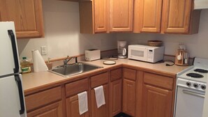 A kitchen with wooden cabinets, a sink, a stove, a microwave, and a toaster. - Sunday River Ski In Ski Out Locke Mountain condo with Pool Jacuzzi (Newry)