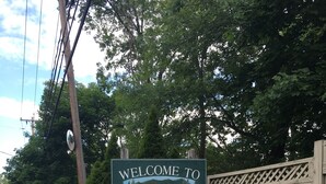 A welcome sign for Bolton Landing with a wooden fence and greenery. - Lake George and Adirondacks (Bolton Landing)