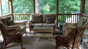 A covered porch with wicker furniture, a ceiling fan, and a view of trees. - Lake George and Adirondacks (Bolton Landing)