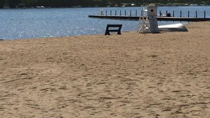 A sandy beach with a lifeguard tower and a bench. - Lake George and Adirondacks (Bolton Landing)