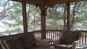 A covered outdoor seating area with wicker furniture and a ceiling fan. - Lake George and Adirondacks (Bolton Landing)