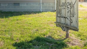 Una casa con techo inclinado, una antena parabólica y un cartel que dice 'Welcome to the Country Lodge'.