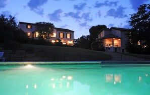 En boligejendom med swimmingpool, et veloplyst hus og en anlagt skrænt.