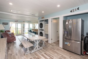 A kitchen with a stainless steel refrigerator, a wooden dining table, and a washing machine.