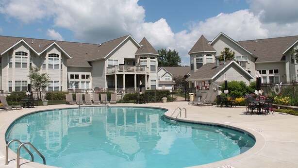 A swimming pool surrounded by a row of houses with a clear sky above.