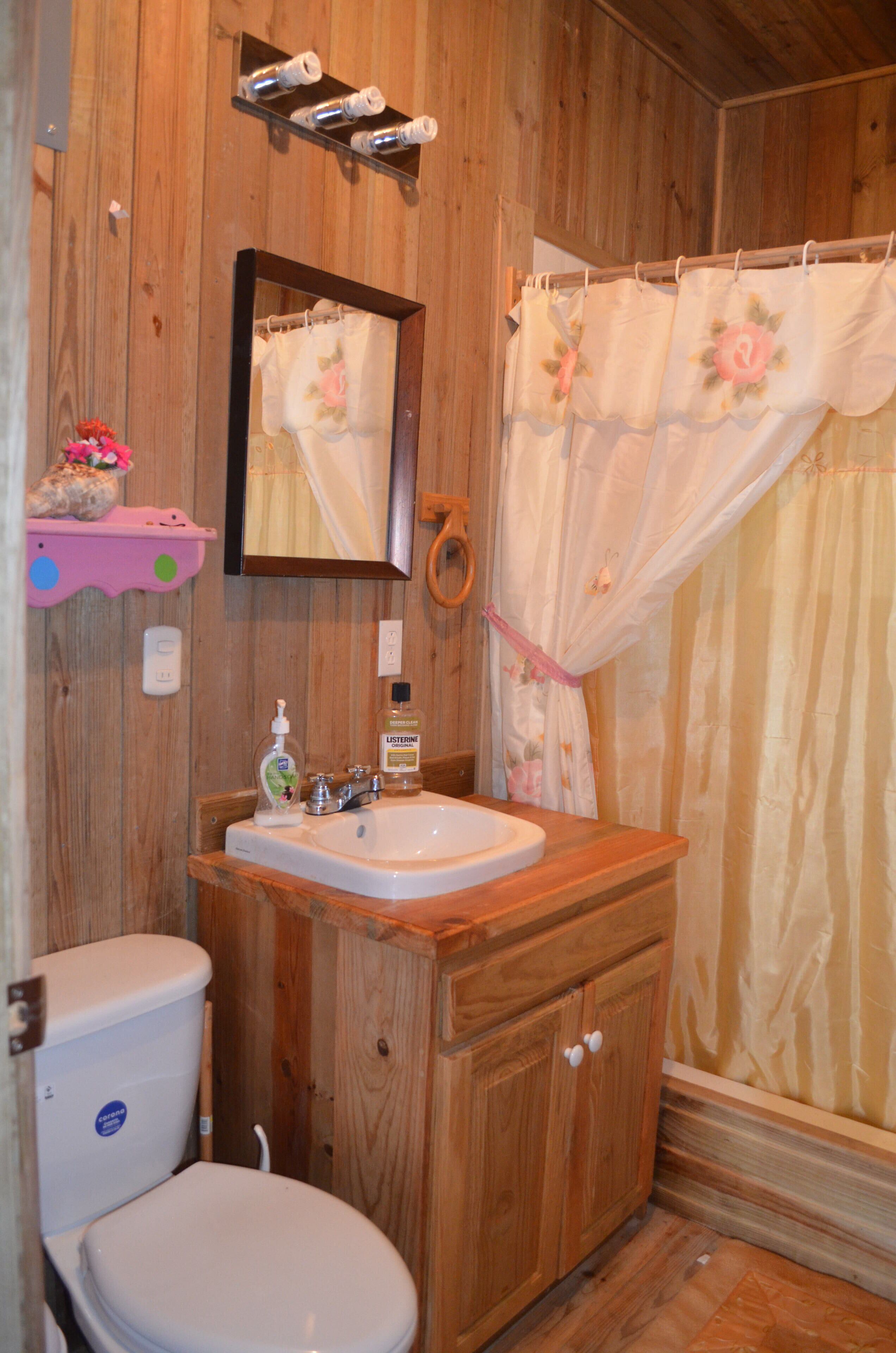 Un baño de madera con inodoro, lavamanos y espejo.
