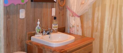 Un baño de madera con inodoro, lavamanos y espejo.