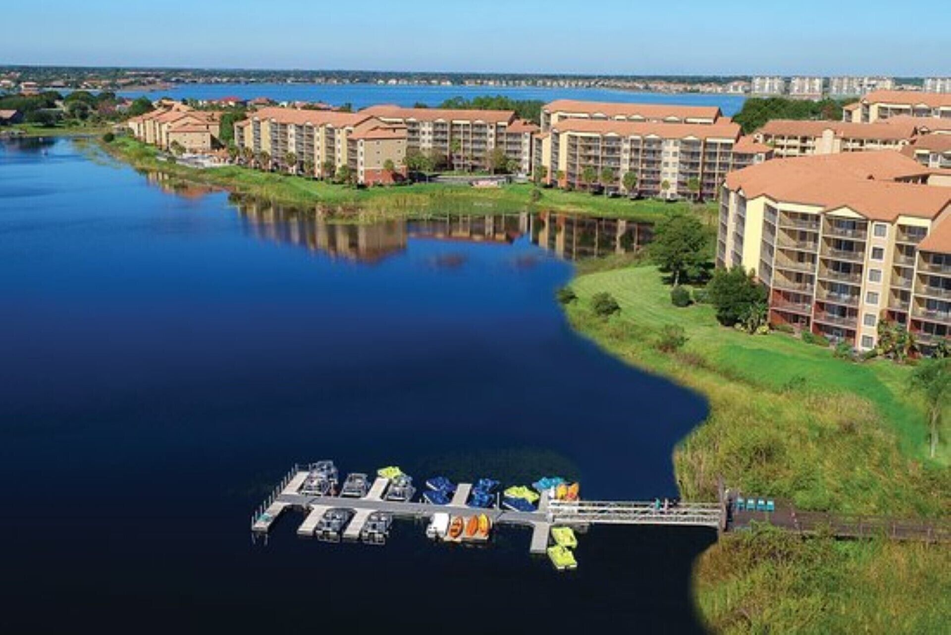 Un hôtel situé au bord de l’eau, composé de plusieurs bâtiments, avec un quai où sont amarrés des bateaux et une rivière paisible.
