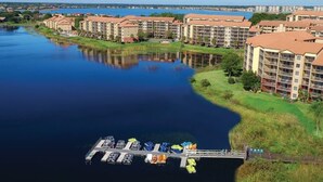 A waterfront hotel with multiple buildings, a dock with boats, and a calm river.
