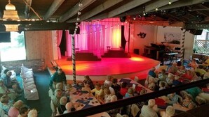 An indoor event space with a stage, audience seating, and wooden beams. - ​Park & Walk: Gretna Lake, Trails & Attractions (Mount Gretna)