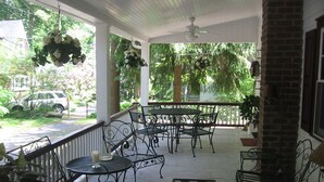 A covered porch with metal furniture, hanging flower arrangements, and a view of a residential street. - ​Park & Walk: Gretna Lake, Trails & Attractions (Mount Gretna)
