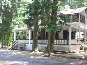 A two-story house with a porch, surrounded by trees.