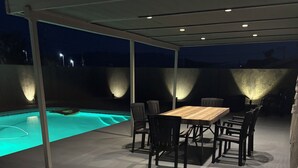 Eine Terrrasse im Freien mit Pool, einem Holztisch und Stühlen.