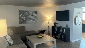 Ein Wohnzimmer mit Sofa, Couchtisch, Fernseher und Lampe.