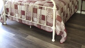 Un lit avec un cadre en métal blanc et une couvre-lit matelassée à motifs à carreaux.