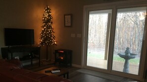 Un salon avec un sapin de Noël, une cheminée, un canapé et un téléviseur.