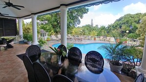 A covered outdoor area with a pool, surrounded by potted plants and outdoor furniture. - Spicy Hill Villa, One Of Jamaica's Best-Kept Secrets. (Port Antonio)