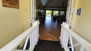 A hallway with a wooden sign reading "SpicyHill Portland Villa," leading to a spacious area with a chandelier and a sign indicating hand sanitizing stations. - Spicy Hill Villa, One Of Jamaica's Best-Kept Secrets. (Port Antonio)
