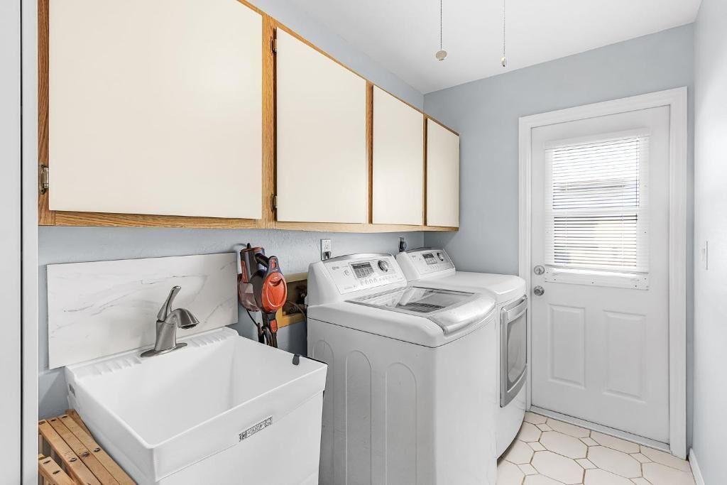 A laundry area with a washing machine, dryer, and sink.