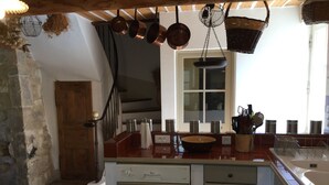 Une cuisine avec un plafond en bois, des casseroles suspendues, un évier et une fenêtre donnant sur un beau paysage.