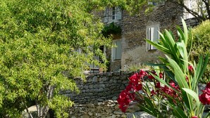 Un bâtiment en pierre au style rustique, caractérisé par un mur en pierre et des volets en bois.