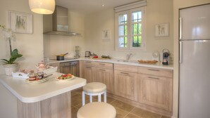 A modern kitchen with a central island, wooden cabinets, a stainless steel refrigerator, and a window providing natural light. - "L'Olivaie side Garden" (Saint-Paul-De-Vence)