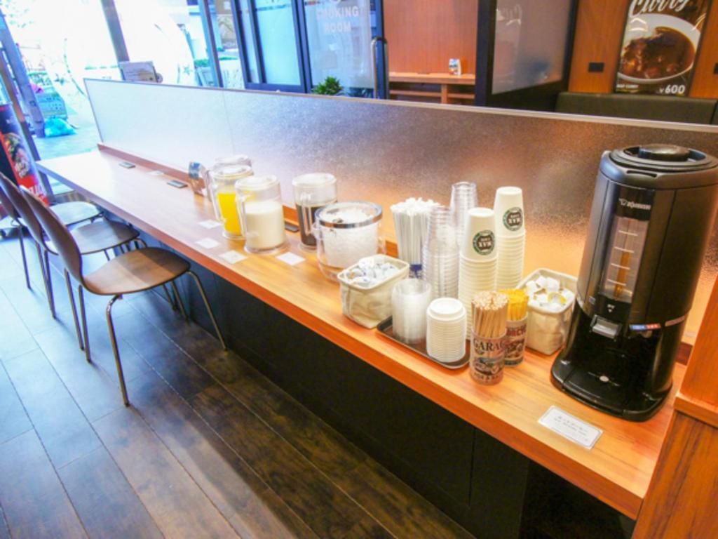 Ein Frühstücksbuffet mit einer Kaffeemaschine, gestapelten Tassen und Beilagen.