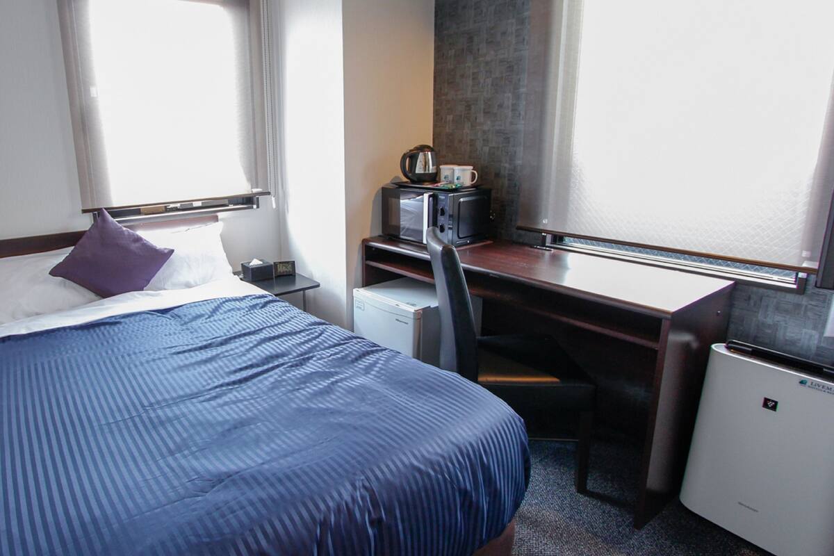 Ein Hotelzimmer mit Bett, Schreibtisch, Mikrowelle und Kühlschrank.