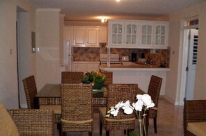 Cozy living space with a dining area and kitchen, featuring a rectangular table and wicker chairs.