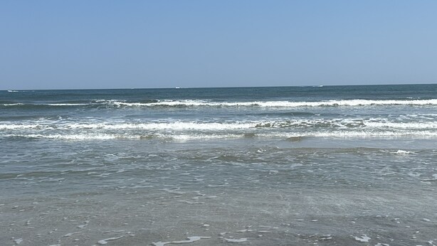 Een strand met golven en een heldere lucht.
