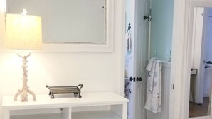 A white vanity with a mirror, a lamp, and a small bench. - Town walking distance-Bridgehampton Cottage (Bridgehampton)