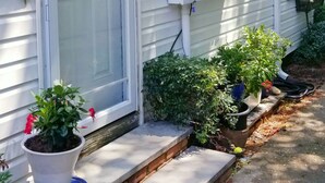 A white house with a 'WELCOME' sign, a front door, and potted plants. - Town walking distance-Bridgehampton Cottage (Bridgehampton)