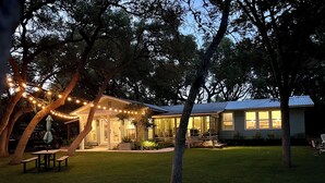 Une maison dotée d’un patio couvert, d’une pelouse et de guirlandes lumineuses.