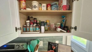 Une cuisine avec des placards ouverts contenant divers aliments et ustensiles de cuisine.