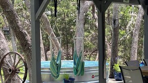 Un patio couvert avec une piscine, des sièges d’extérieur et des hamacs suspendus.
