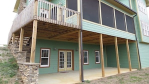 A two-story house with a balcony, large windows, and a stone chimney.