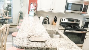 A kitchen with a long countertop, a sink, and a stove.