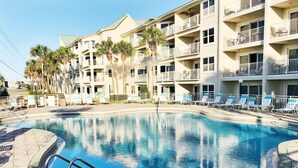 A swimming pool with lounge chairs and a building with balconies in the background.