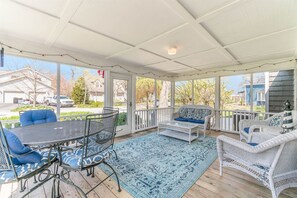 Une terrasse couverte, aménagée avec du mobilier d’extérieur, une table et un tapis à motifs.