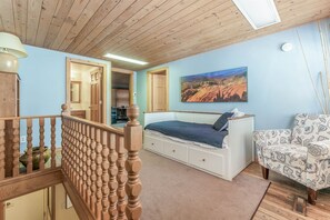 Une chambre à coucher avec un lit, une chaise, un tableau et un escalier.
