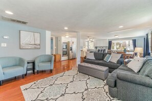 A spacious living area with a sofa set, two armchairs, a patterned rug, and a kitchen in the background. - Spacious 5-bedroom home in Saugatuck, short walk to downtown, perfect for family getaways. (Saugatuck)
