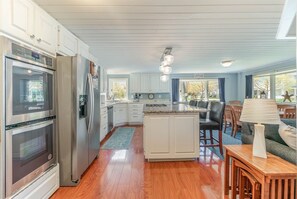 A modern kitchen with stainless steel appliances, a central island, and a dining area with a table and chairs. - Spacious 5-bedroom home in Saugatuck, short walk to downtown, perfect for family getaways. (Saugatuck)