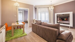 Ein modernes Wohnzimmer mit einer Couch, einem Esstisch mit Stühlen und einem an der Wand befestigten Fernseher.