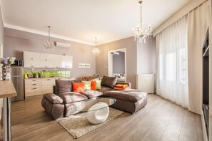 A modern living room with a sectional sofa, a glass coffee table, and a chandelier.