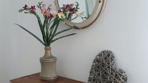 Une coiffeuse en bois avec un miroir, un vase de fleurs et un objet décoratif sur l’étagère.