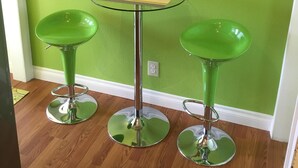 A small, round glass table with a metal base, flanked by two green bar stools with metal bases. - Steps to the water on both sides!! (San Diego)