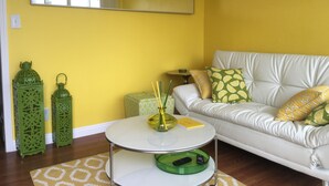 A living room with a yellow wall, a white sofa, and a round coffee table. - Steps to the water on both sides!! (San Diego)