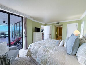 Ein Hotelzimmer mit Bett, Fernseher, Schreibtisch und Stuhl. Ein Balkon bietet Blick auf das Meer.